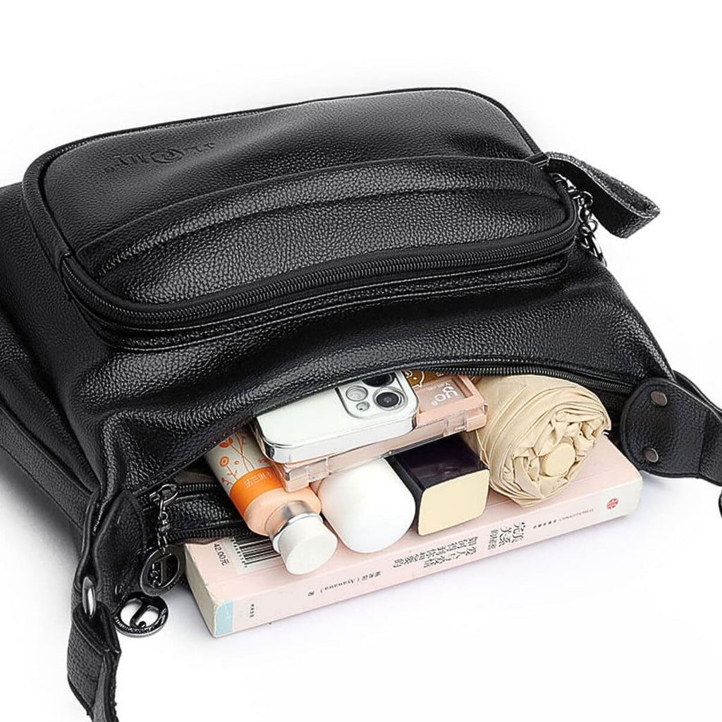 Black leather sling bag shown open with phone cosmetics and essentials inside multiple compartments