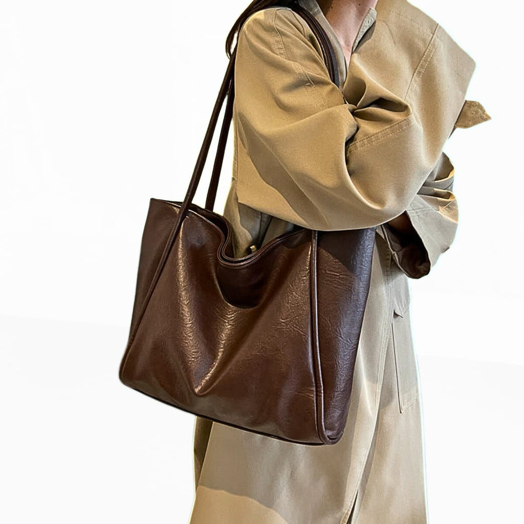 Woman carrying brown leather tote bag with shoulder straps